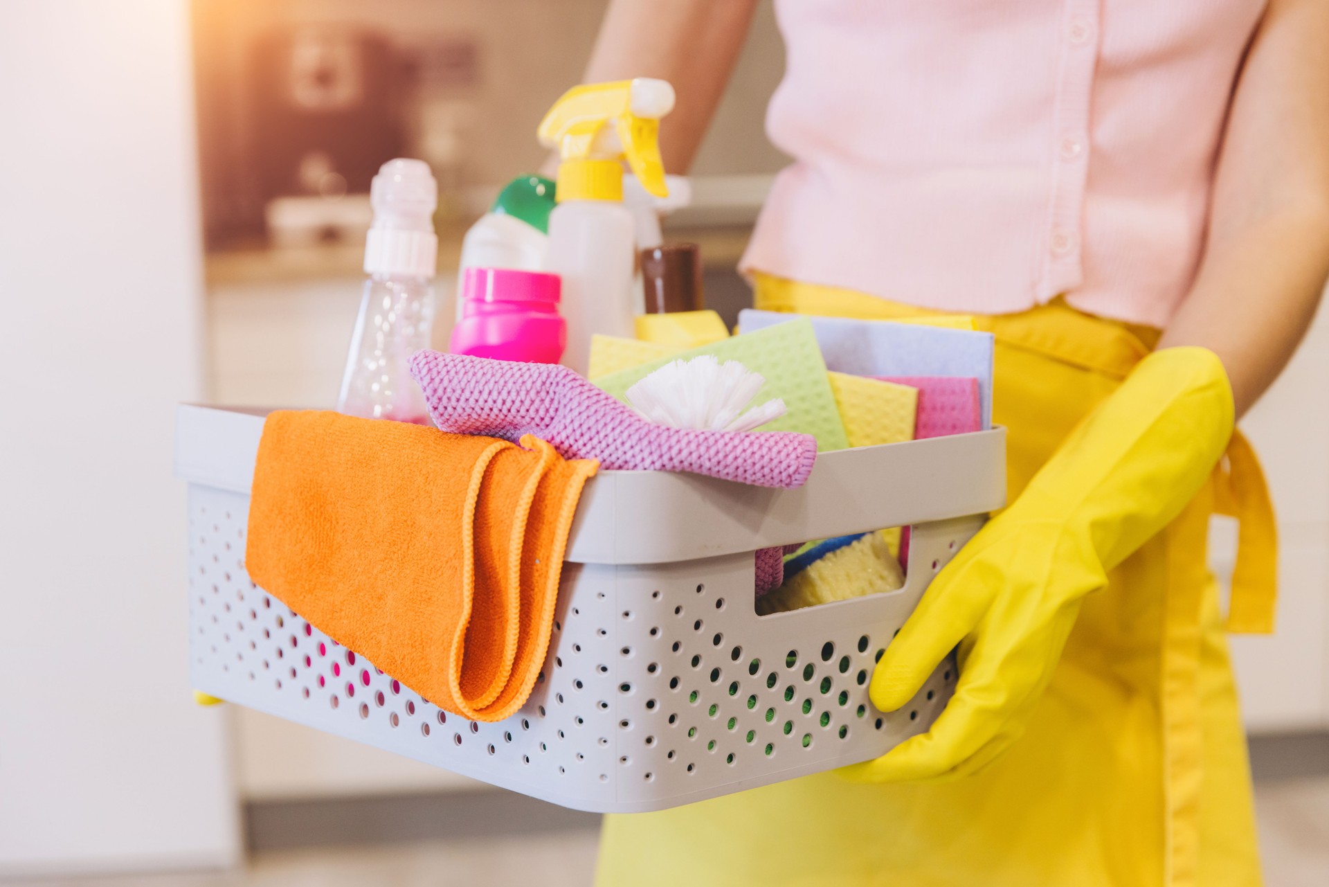 Housekeeper holding cleaning products and equipment in basket
